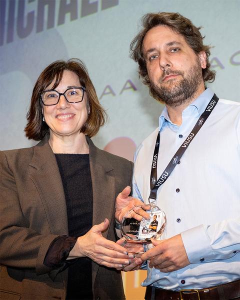 A man accepting a ccaa award from a woman.